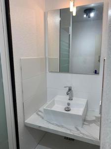 La salle de bains blanche est pourvue d'un lavabo et d'un miroir. dans l'établissement studio Cosy proche hyper centre, à Quimper