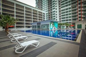 a swimming pool with lounge chairs in front of a building at High Floor studio Austin Regency Mount Austin w Balcony 3 plus 1pax 5 mins AEON in Johor Bahru