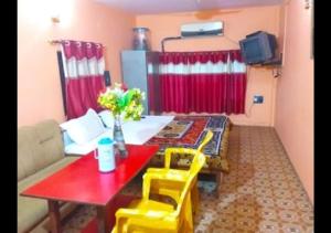 un soggiorno con tavolo rosso e sedie gialle di Zeal Guesthouse By WB Inn a Kānpur