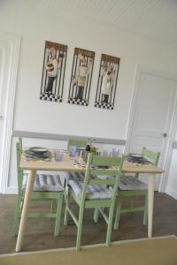 uma mesa de jantar com cadeiras verdes e uma mesa com pratos em Renovated French Country House for Six - A Home for Your Next Holiday em Hercé
