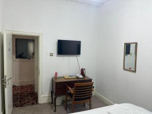 Habitación con escritorio y TV en la pared. en Saji Hotel Illford en Ilford