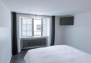 a bedroom with a white bed and a window at Marktgasse Hotel in Zurich