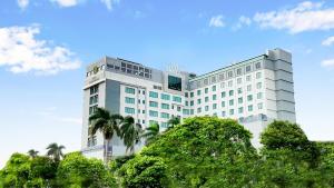 a white building with trees in front of it at The Excelton Hotel in Palembang