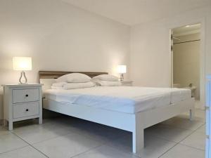 1 dormitorio blanco con 1 cama grande y 2 lámparas en Süsse Wohnung Apt 106 en Locarno