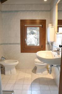 bagno con lavandino, servizi igienici e finestra di Appartamento Emanuel a Livigno