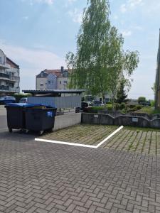 un estacionamiento con dos cubos de basura y un árbol en BRISE Business Apartment nahe Leipziger Messe - Porsche - BMW - DHL - WLAN - Parkplatz - business travelers only, en Leipzig