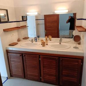 ein Badezimmer mit zwei Waschbecken und einem großen Spiegel in der Unterkunft Villa CITRONS VERTS dans un parc arboré vue mer in Cap Skirring