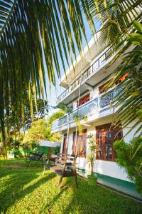 a house with a palm tree in front of it at Jaya Tomodachi in Kandy