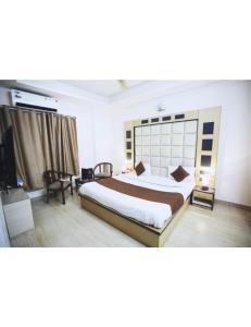 a bedroom with a large bed and a television at Hotel Kolam, Dehradun in Dehradun