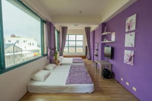 Habitación con 2 camas y pared púrpura. en Meet Bay B&B, en Xiyu