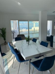 a dining room with a white table and blue chairs at Sapphire Penthouse in Tropea