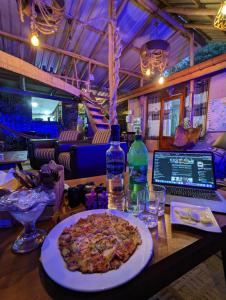 a table with a pizza and a laptop on it at Noname Hostel And Cafe in Ella