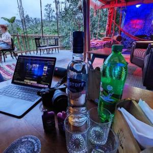 a table with a bottle of water and a laptop at Noname Hostel And Cafe in Ella