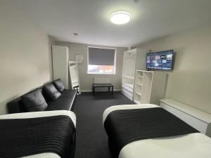 a room with two beds and a couch and a tv at Hosted By Ryan - Studio Apartment in Liverpool