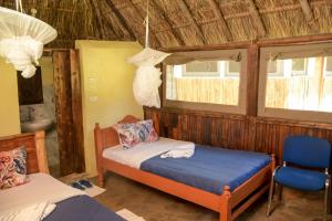 um quarto com uma cama, uma cadeira e janelas em Giraffe Hills Mara Camp em Masai Mara