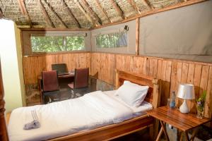 a bedroom with a bed and a desk and a table at Giraffe Hills Mara Camp in Masai Mara