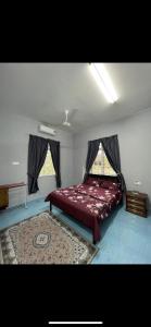 a bedroom with a bed and a rug and two windows at Casa Harmony in Tanah Merah