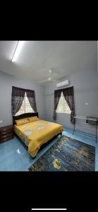 a bedroom with a bed with a yellow blanket and two windows at Casa Harmony in Tanah Merah