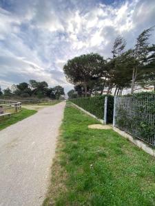 a dirt road next to a fence with trees at Complesso Mosaico NO PISCINA Per il Check in Agenzia Viale Francesco Petrarca 391 lido Adriano Ra in Lido Adriano