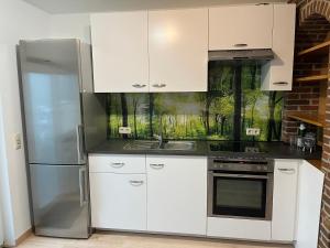 a kitchen with white cabinets and a stainless steel refrigerator at Ferienwohnung Rüth in Kall