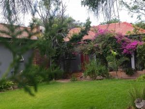 a house with a yard with green grass and flowers at Royal Karoo Cottage unit 2 in Beaufort West +7 photos