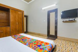 a bedroom with a bed and a tv on the wall at FabHotel Harmony in Colonelganj