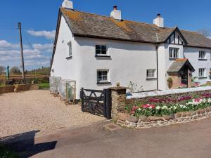 a white house with flowers in front of it at The Old Mill Cottage in Okehampton