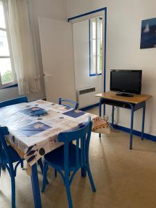 Habitación con mesa con sillas y TV. en Les Tilleuls en Le Pouliguen