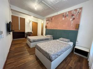 Zimmer mit 2 Betten und Wandgemälde in der Unterkunft Jojos Nascere in Aizawl