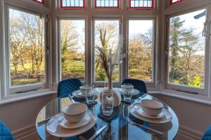 ein Esszimmer mit einem Glastisch, Stühlen und Fenstern in der Unterkunft Calverley Place -Long Stay Offer in Royal Tunbridge Wells