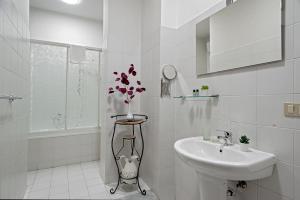 un bagno bianco con lavandino e vaso di fiori di The Journalist House a Livorno