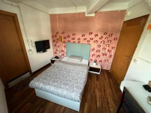 um quarto com uma cama e uma parede rosa em Jojos Nascere em Āīzawl