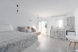 a white bedroom with a bed and a kitchen at Sonia in Mýkonos City