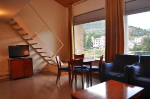een woonkamer met een tafel en stoelen en een televisie bij Aparthotel Solé in Pobla de Segur