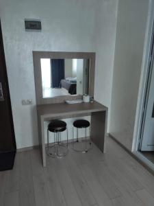 uma casa de banho com um toucador com 2 bancos e um espelho em MikePalace em Batumi