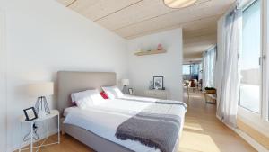 um quarto com uma grande cama branca e uma grande janela em Magnificent modern apartments in the city center em La Chaux-de-Fonds