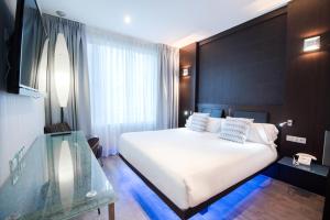 Un dormitorio con una gran cama blanca y una ventana en Petit Palace President Castellana, en Madrid