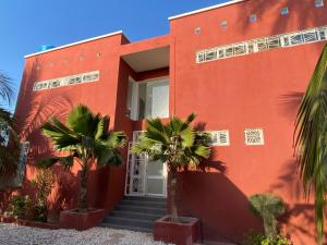 una casa roja con palmeras delante en Villa avec piscine entre plage et Siné Saloum, en Palmarin