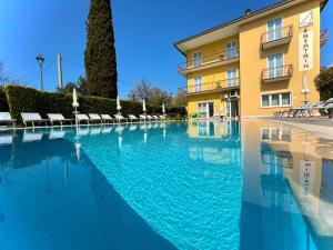 a swimming pool in front of a building at Bardolino Wein Apartments in Bardolino
