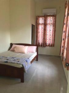 a bedroom with a bed and two windows with curtains at Homestay Docmac Wakaf Che Yeh in Kota Bharu