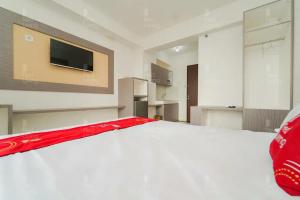 a bedroom with a white bed and a flat screen tv at RedLiving Apartemen Riverview Residence - TOHA Room Tower Mahakam in Tegalgede