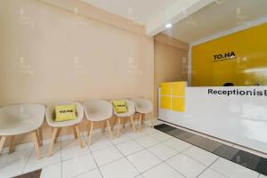 a waiting room with white chairs and yellow signs at RedLiving Apartemen Riverview Residence - TOHA Room Tower Mahakam in Tegalgede