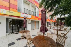 a patio with tables and umbrellas in front of a building at RedLiving Apartemen Riverview Residence - TOHA Room Tower Mahakam in Tegalgede