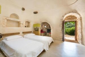 2 letti in una camera da letto con porta ad arco di Trulli di Monte Reale by BarbarHouse a Cisternino