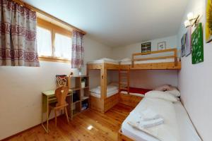 a bedroom with two bunk beds and a desk at Apartment Sur Puoz 1A in Samedan