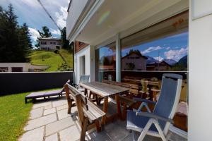 a patio with a wooden table and chairs on it at Apartment Sur Puoz 1A in Samedan