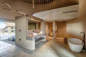 a bathroom with a tub and a sink and a bath tub at TimBila Private Villa in Omaruru