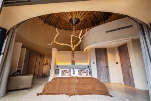 a bedroom with a bed with a tree on the ceiling at TimBila Private Villa in Omaruru