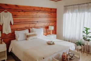 1 dormitorio con 1 cama blanca grande y cabecero de madera en Hostería El Coirón en Esquel