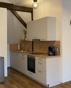 a kitchen with white cabinets and a sink at Wunderschöne Ferienwohnung auf dem Bauernhof in Greven